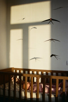 Baby sleeps in crib with paper birds above