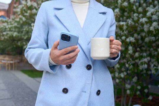Woman holding cup of coffee and smartphone