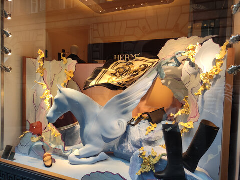 Rome, Italy - June 03, 2026: Decorative window display featuring a white winged horse sculpture, luxury items, and a Hermes scarf in an upscale retail setting