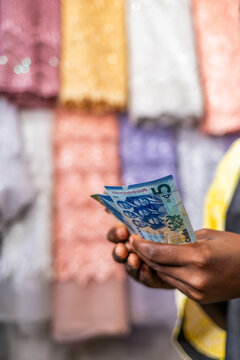 Ghana entrepreneur holding ghana cedis showing success in small business textiles shop
