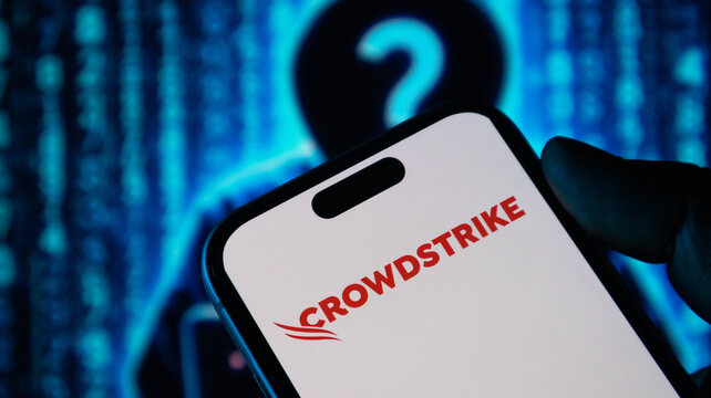 Crowdstrike security software logo on mobile phone screen held against hacker background.
