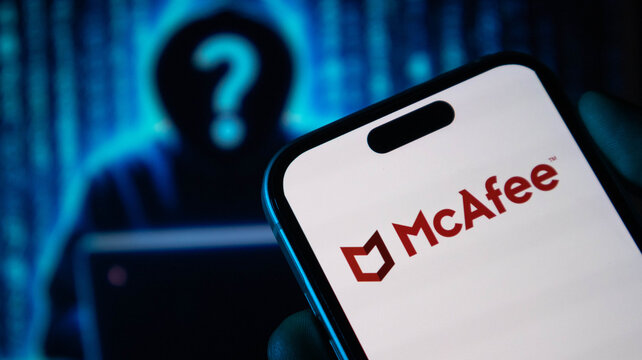 Person holding smartphone showing mcafee antivirus software logo on bright display screen.