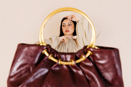 Woman posing behind luxury handbag 