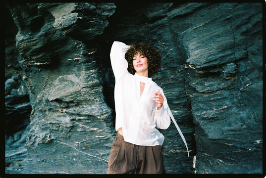 Woman in stylish outfit on rocky coastline