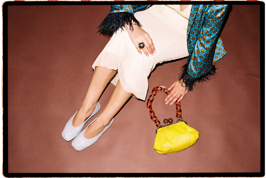 Woman sitting with yellow handbag, shoes, and jacket