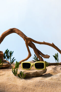Stylish yellow sunglasses resting on a rock amidst a sandy surface