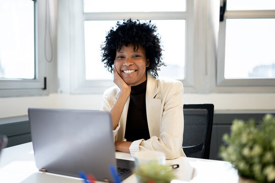 Confident Black woman smiling working on laptop in office