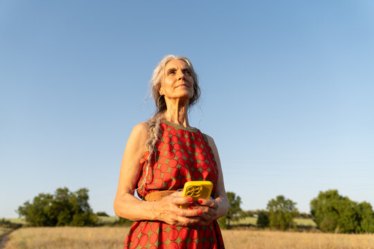 Senior woman using phone blue sky