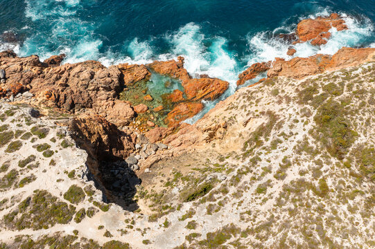 Natural rockpool amongst by colorful boulders along a rugged coastline