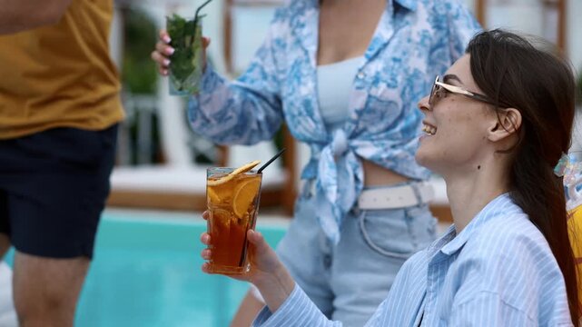 Friends celebrating together with colorful drinks beside the swimming pool, sharing laughter and unforgettable summer moments. Pool party, friendship and joyful lifestyle concept
