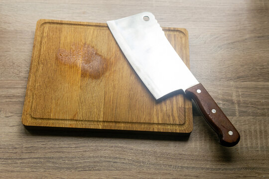 Chopping board with knife on wooden background. Top view. Copy space.