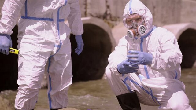 Scientists testing wastewater samples with strip at drainage culvert