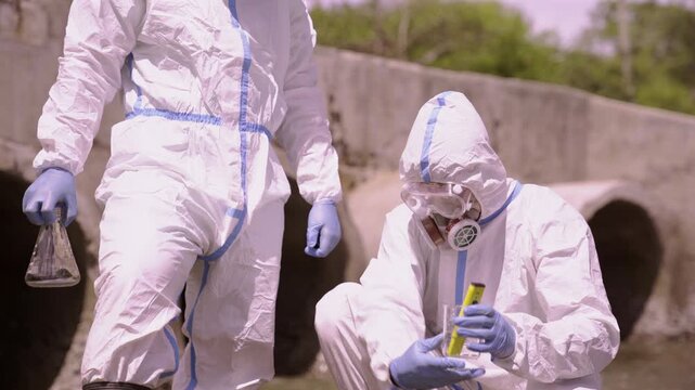 Scientists testing wastewater samples with strip at drainage culvert