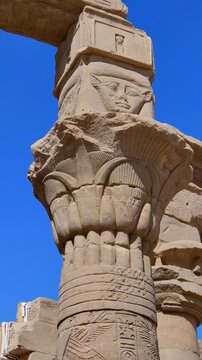 Upward view of ornate floral capitals on Ptolemaic columns at Philae Temple, Aswan Egypt. Elegant ancient architecture against vivid blue sky. Travel and history content.
