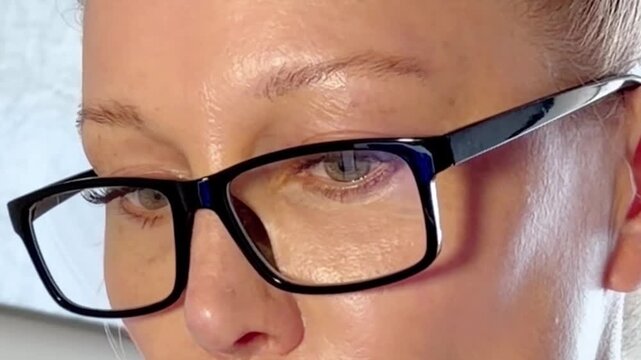 Woman Working Late at Night on a Laptop with the Blue Glow of the Screen Illuminating Her Face and Glasses