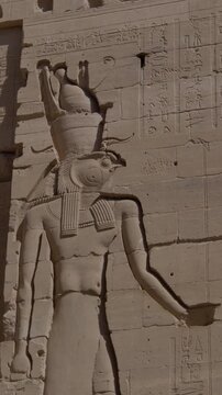 Detailed reliefs of ancient Egyptian deities carved on the walls of the Philae Temple, illuminated by sunlight highlighting intricate hieroglyphs and figures. Egypt.