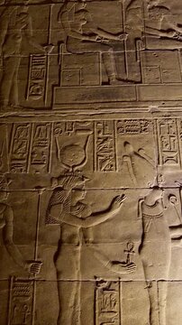 Detailed reliefs of ancient Egyptian deities and hieroglyphs carved on the walls of the Philae Temple. Egypt.