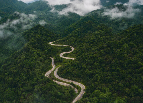 Aerial view of winding road through green mountainous landscape with clouds transparent background