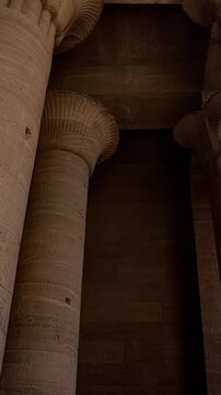 Ancient Egyptian Philae Temple. interior with massive carved stone columns covered in hieroglyphs, low angle view highlighting detailed reliefs and architectural grandeur.
