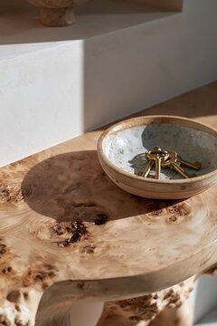 Handcrafted ceramic key bowl on burl wood table in warm minimalist Scandinavian interior