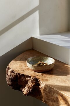 Ceramic catchall bowl with brass keys on live edge wood console in minimalist luxury interior