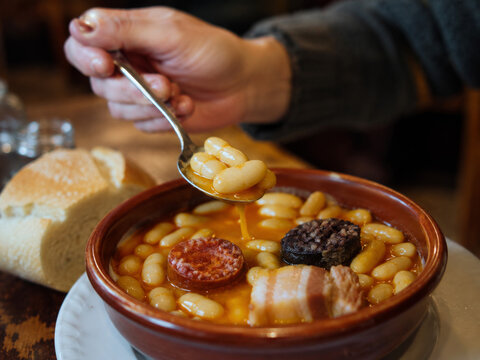 Comida tradicional en un plato con jud&iacute;as, chorizo y pan en un restaurante