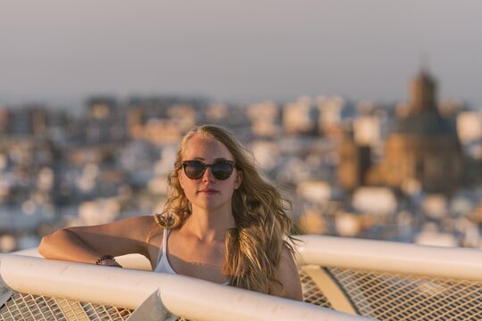 Young woman in sunglasses looks into the camera, Plaza de la Encarnacion, behind houses, Seville, Andalusia, Spain
