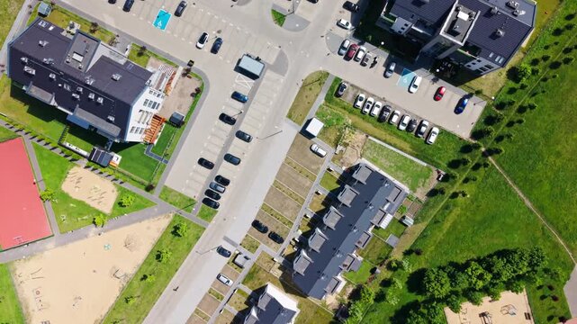 residential district aerial view apartment buildings parking lot playground green infrastructure. bird's eye drone shot of a modern suburban neighborhood development with organized parking spaces, fam