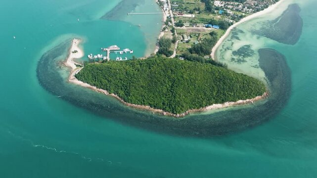 Dense green vegetation covering a small island with clear turquoise waters and boats nearby. Lipa Noi. Ko Samui, Thailand.