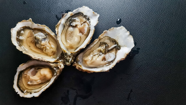 Fresh opened oysters on black background.