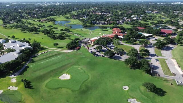 Club house fairway architecture overlooks sweeping golf vistas featuring sand bunkers practice grounds. Well maintained lawns span horizontal horizon lines beneath bright skies in Irving, Texas
