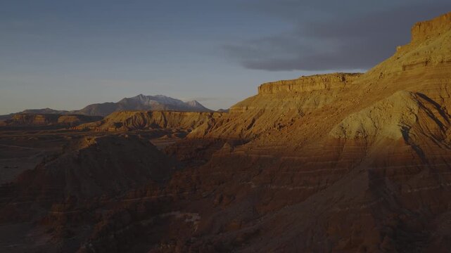 An aerial flyover sandstone rock formation and cliffs near the Henry Mountains at sunrise, Utah