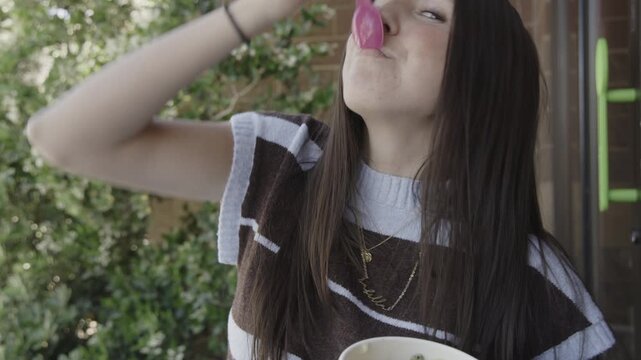 A young caucasian woman is eating frozen yogurt and teasing the camera with a bite from her spoon, St. George, Utah