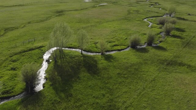 An aerial flyover of a stream running through marshland and meadows, Kamas, Utah