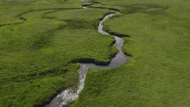 An aerial flyover of a stream running through marshland and meadows, Kamas, Utah