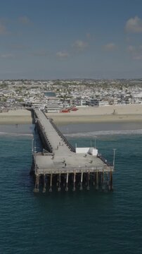 An aerial flyover vertical video of the Newport pier and beach, Newport Beach, California