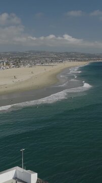 An aerial flyover vertical video of the Newport pier and beach, Newport Beach, California