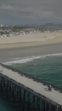 An aerial flyover vertical video of the Newport pier and beach, Newport Beach, California