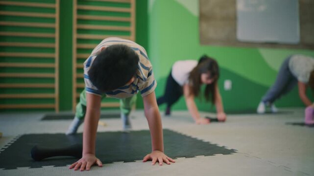 Children are actively participating in a fitness class, performing exercises with small dumbbells.