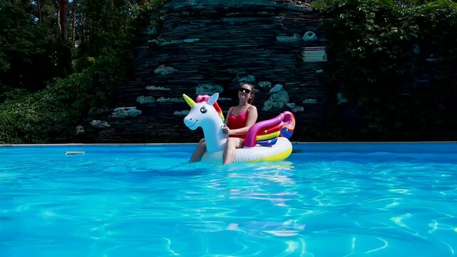 Woman on inflatable unicorn pool float in pool in hotel. Summer holidays, enjoying summer vacations 
