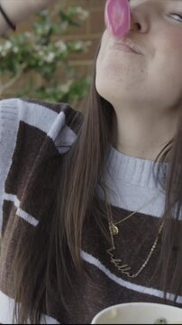 A young woman is eating frozen yogurt and teasing the camera with a bite from her spoon, vertical video, St. George, Utah