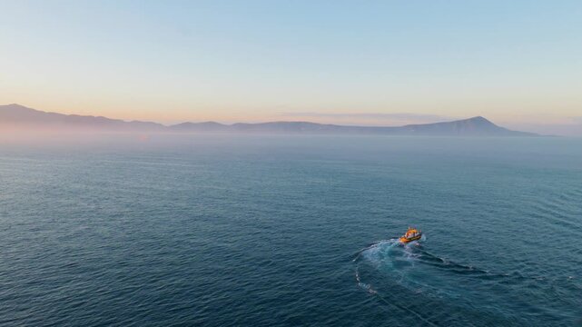 Maritime vessel sailing past Mount Vesuvius in Bay of Naples at sunrise