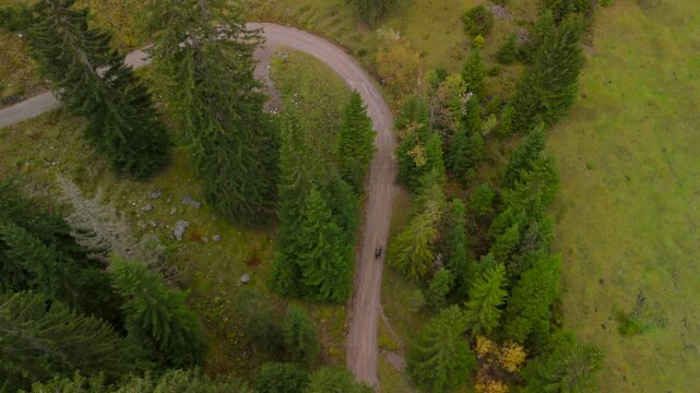 Aerial drone view of a man pushing a gravel bike uphill toward Soinsee lake. This moody autumn ascent is located near Bayrischzell in the Mangfallgebirge mountains, Bavarian Prealps, Germany