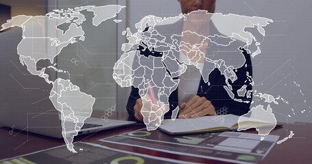 Businesswoman writing in notebook with pink pencil, checking charts on laptop, world map overlaying © vectorfusionart