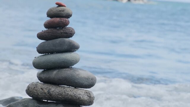 beach with cairn rocks, zen-like pebbles stacked in balanced pyramid against ocean waves, Balanced stones on beach, Meditation and mindfulness, harmony, travel, and serenity coastal retreats