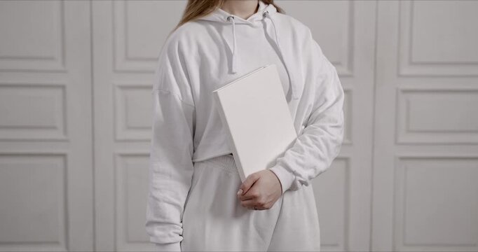Woman in White Hoodie Holding Blank Book Mockup