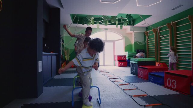 Children participate in a fun fitness session, navigating an agility course in a vibrant gym. Youngsters develop their coordination and balance through active play and exercise.