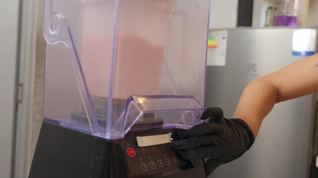Female barista making protein shake in blender