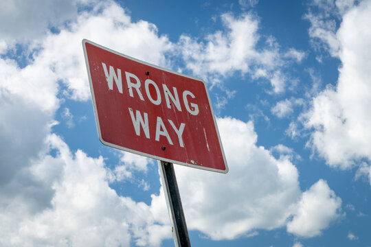 wrong way highway warning sign against cloudy sky