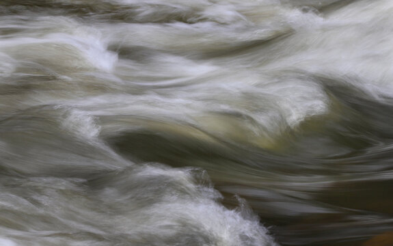Schnell flie&szlig;endes Wasser in einem Bach im Hevetal, NRW, Deutschland,  mit Langzeitbelichtung um den weichen, flie&szlig;enden Effekt zu erzielen. Die Zeit flie&szlig;t, der Moment bleibt.
